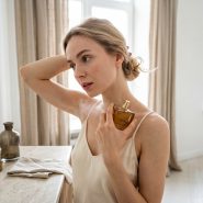 Femme appliquant du parfum dans une pièce lumineuse