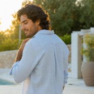 Homme souriant près d’une piscine au coucher du soleil