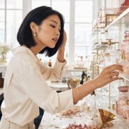 Femme choisissant un flacon de parfum rose