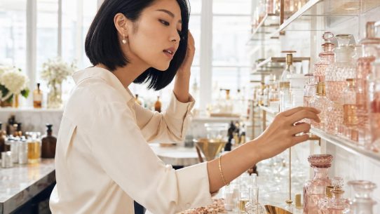 Femme choisissant un flacon de parfum rose