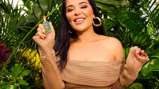 Femme souriante tenant un parfum en jungle