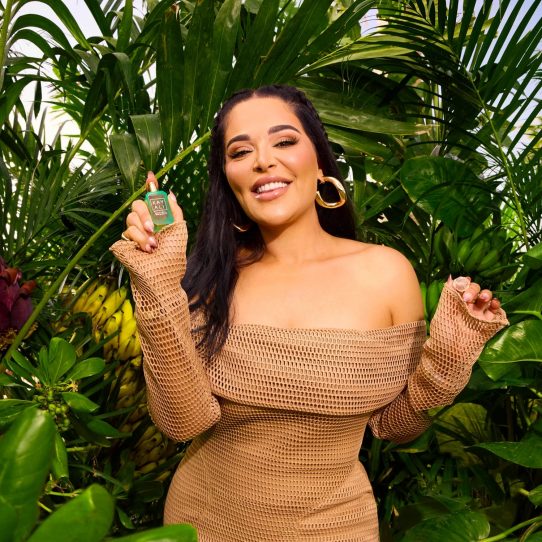 Femme souriante tenant un parfum en jungle
