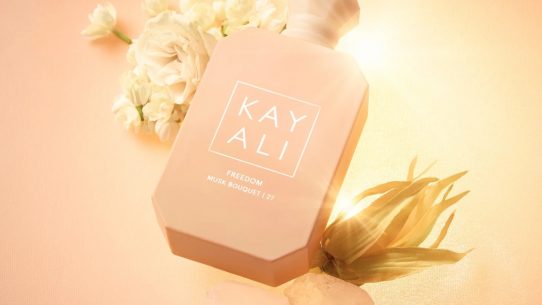 Flacon Kayali Freedom entouré de fleurs et cristaux