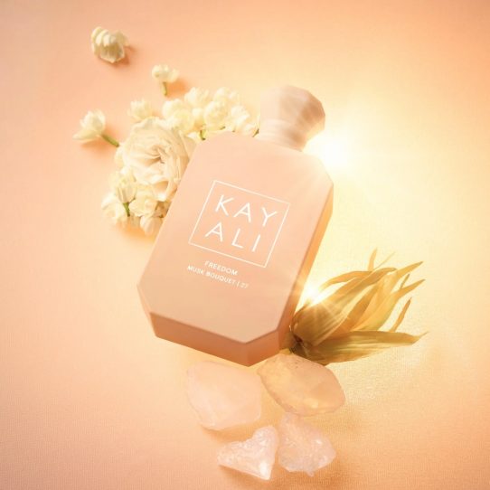 Flacon Kayali Freedom entouré de fleurs et cristaux