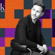 David Benedek, fondateur de BDK Parfums, en portrait noir et blanc sur fond de damier orange et violet