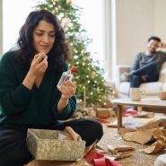 Femme découvrant un parfum offert près du sapin de Noël